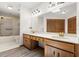 Double vanity bathroom with warm cabinets, large mirror, and shower at 912 Fruitwood Pl, Port Orange, FL 32127