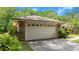 A two-car garage showcases a brick facade complemented by dark sconces and mature landscaping at 912 Fruitwood Pl, Port Orange, FL 32127