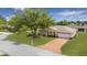 Charming single-story home featuring a brick driveway, manicured lawn, and a large shade tree at 10031 Sw 62Nd Cir, Ocala, FL 34476