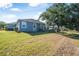 Backyard featuring a gray house, large tree, and lots of grass at 117 Hagge Dr, Daytona Beach, FL 32124