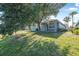 Backyard featuring green grass, large tree, and gray house at 117 Hagge Dr, Daytona Beach, FL 32124