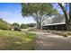 View of long porch along the side of a white community building with mature trees and landscaping at 3513 Kilgallen Ct, Ormond Beach, FL 32174