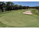 View of a manicured golf course green with a yellow flag and well-maintained sand traps at 3513 Kilgallen Ct, Ormond Beach, FL 32174