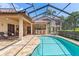 Pool area with a screened enclosure, a pool, stone patio, and an outdoor kitchen at 3513 Kilgallen Ct, Ormond Beach, FL 32174