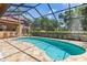 Backyard pool surrounded by a screened enclosure and a stone patio with an outdoor kitchen at 3513 Kilgallen Ct, Ormond Beach, FL 32174