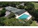 Aerial view of tennis courts and large swimming pool with lane markers, surrounded by trees at 3513 Kilgallen Ct, Ormond Beach, FL 32174