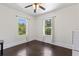 Sunlit bedroom featuring neutral walls, dark wood floors, two windows, and a ceiling fan at 509 Park Dr, Daytona Beach, FL 32114
