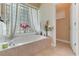 A luxurious bathtub with tile surround and a window with decorative glass block for natural light at 69 Coquina Ridge Way, Ormond Beach, FL 32174