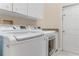 Bright laundry room with modern washer and dryer, white cabinets, and a neutral color scheme at 69 Coquina Ridge Way, Ormond Beach, FL 32174