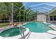 Sparkling pool and hot tub surrounded by a screened enclosure, lush landscaping, and comfortable seating at 69 Coquina Ridge Way, Ormond Beach, FL 32174