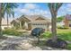 Single-story house showcasing a well-maintained yard, a mature tree, and a two-car garage with driveway parking at 1956 Southern Dunes Blvd, Haines City, FL 33844