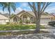 Charming single-story home featuring a manicured lawn, mature trees, and a two-car garage with driveway at 1956 Southern Dunes Blvd, Haines City, FL 33844