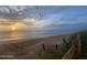 Serene beach scene at sunrise with calm ocean waves, a sandy shore, and a dune fence in view at 3000 Ocean Shore Blvd # 150, Ormond Beach, FL 32176