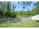 Scenic backyard featuring a white fence, green grass, mature trees, and a tranquil pond view at 5 Cantilever Ct, Ormond Beach, FL 32174