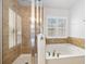 Bathroom featuring soaking tub, glass-enclosed shower, and natural tile surround at 5 Cantilever Ct, Ormond Beach, FL 32174