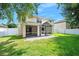 Exterior view of the home's backyard with covered patio, screen porch, and white privacy fence at 5 Cantilever Ct, Ormond Beach, FL 32174