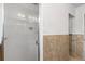 Walk-in shower featuring white tiled walls, glass door and a lighting fixture overhead at 1159 Magnolia Ave, Daytona Beach, FL 32114