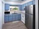 Cozy kitchen featuring blue cabinets, modern appliances, and natural light from the window at 1301 Oakwood Ave, Daytona Beach, FL 32114