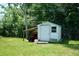 White storage shed with small window, lawn mower parked underneath attached shelter on grassy lot at 1301 Oakwood Ave, Daytona Beach, FL 32114