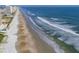 High rise ocean front view shows the beach with surfers and waves on a bright sunny day at 1504 N Atlantic Ave, Daytona Beach, FL 32118