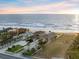 Aerial view showcases the home, bordering the ocean, near other homes along a landscaped street at 1504 N Atlantic Ave, Daytona Beach, FL 32118