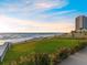 Relaxing beach view with modern high rise, grassy lawn and calming ocean waves at 1504 N Atlantic Ave, Daytona Beach, FL 32118