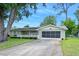 Single-story home featuring a well-maintained lawn, mature trees, driveway, and a screened garage at 241 Sanchez Ave, Ormond Beach, FL 32174