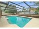 A beautiful screened-in pool features cool water, brick enclosure, privacy fence, and mature trees at 2468 Scottville Ave, Deltona, FL 32725
