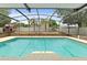 A beautiful screened-in pool features cool water, brick enclosure, privacy fence, and mature trees at 2468 Scottville Ave, Deltona, FL 32725
