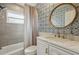 Updated bathroom featuring a tub and shower combination, patterned wallpaper, and a large round mirror at 290 Greenwood Cir, Ormond Beach, FL 32174