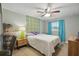 Comfortable bedroom with a ceiling fan, a patterned accent wall, and bright turquoise drapes at 290 Greenwood Cir, Ormond Beach, FL 32174