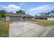 Well-kept single-story home featuring a large driveway, attached garage, and manicured lawn at 290 Greenwood Cir, Ormond Beach, FL 32174