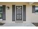 Close up view of the front door featuring gray shutters and stylish exterior lighting at 290 Greenwood Cir, Ormond Beach, FL 32174