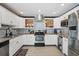 Well-lit kitchen features white cabinets, stainless steel appliances, stylish backsplash, and granite countertops at 290 Greenwood Cir, Ormond Beach, FL 32174
