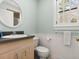 Cozy bathroom with a round mirror, gray countertop, and white wainscoting at 37918 N County Road 44A, Eustis, FL 32736
