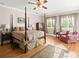 Spacious bedroom with hardwood floors, a four-poster bed, and two windows providing plenty of light at 37918 N County Road 44A, Eustis, FL 32736