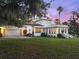 View of a luxurious white home with a red tile roof surrounded by lush landscaping at 37918 N County Road 44A, Eustis, FL 32736