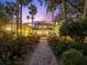 Stunning exterior view of the home's courtyard, brick pathway, lush garden, fountain, and palm trees at 37918 N County Road 44A, Eustis, FL 32736