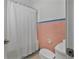 Cozy bathroom featuring retro pink tiling, toilet, and shower behind white curtain at 401 N Oleander Ave, Daytona Beach, FL 32118