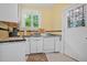 Quaint kitchen featuring stainless steel sink, white cabinets, and a unique window view with yellow walls at 401 N Oleander Ave, Daytona Beach, FL 32118