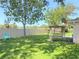 Expansive backyard with lush green grass, a charming swing, privacy fence, and mature trees at 613 Clairmont Ln, South Daytona, FL 32119