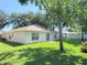 Well-maintained backyard featuring a lush green lawn, mature trees and a sliding door entry to the home at 613 Clairmont Ln, South Daytona, FL 32119