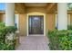 Close-up of the front entrance with tiled porch, decorative columns, and a solid wood door with glass panels at 881 Westline Ave, Deltona, FL 32725