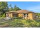 Exterior view of house with neutral paint, fenced-in yard and screened-in patio surrounded by mature trees at 881 Westline Ave, Deltona, FL 32725