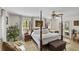 Elegant main bedroom with a four-poster bed, plush rug, and a seating area with natural light from windows at 1 Crooked Bridge Way, Ormond Beach, FL 32174