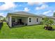 Back exterior showcasing a covered patio and expansive lawn with palm tree and flower bed at 5539 Estero Loop, Port Orange, FL 32128