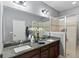 This bathroom features granite countertops, dual sinks, a large mirror, a glass shower and gray tile floors at 5539 Estero Loop, Port Orange, FL 32128