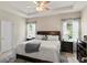 This main bedroom features a tray ceiling, ceiling fan, light hardwood floors and ensuite bathroom access at 5539 Estero Loop, Port Orange, FL 32128