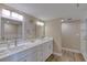 Bright bathroom featuring double sinks with modern fixtures, decorative lighting, and wood look floors at 1239 Ocean Shore Blvd # 11D, Ormond Beach, FL 32176