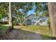View of the backyard with trees, blue siding on house and green lawn at 1317 Northside Dr, Ormond Beach, FL 32174